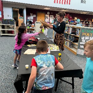 Students learn about a rice sifter from a parent volunteer.